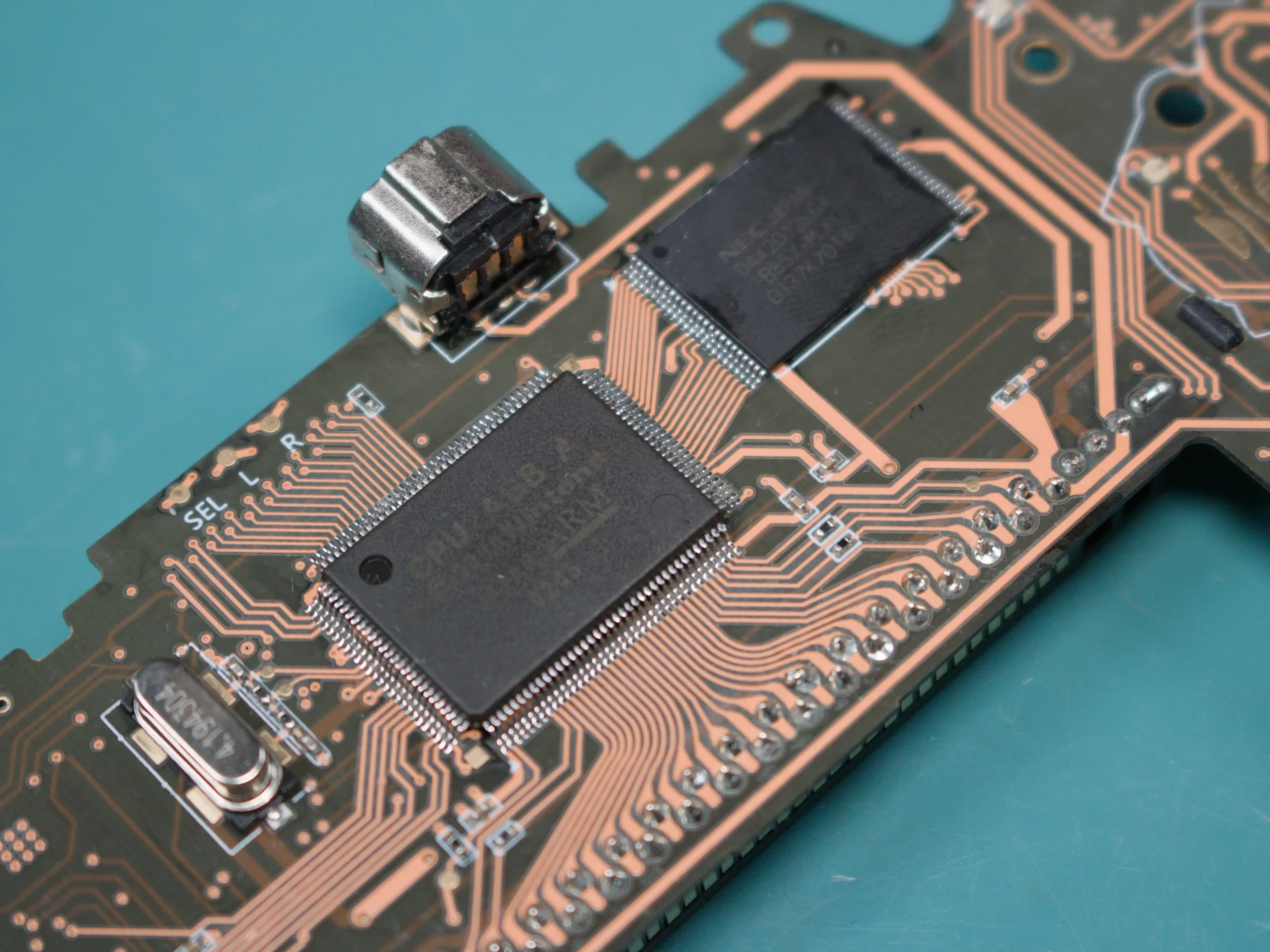 Close-up of a Game Boy Advance motherboard showing the CPU and memory chips soldered near the link port
