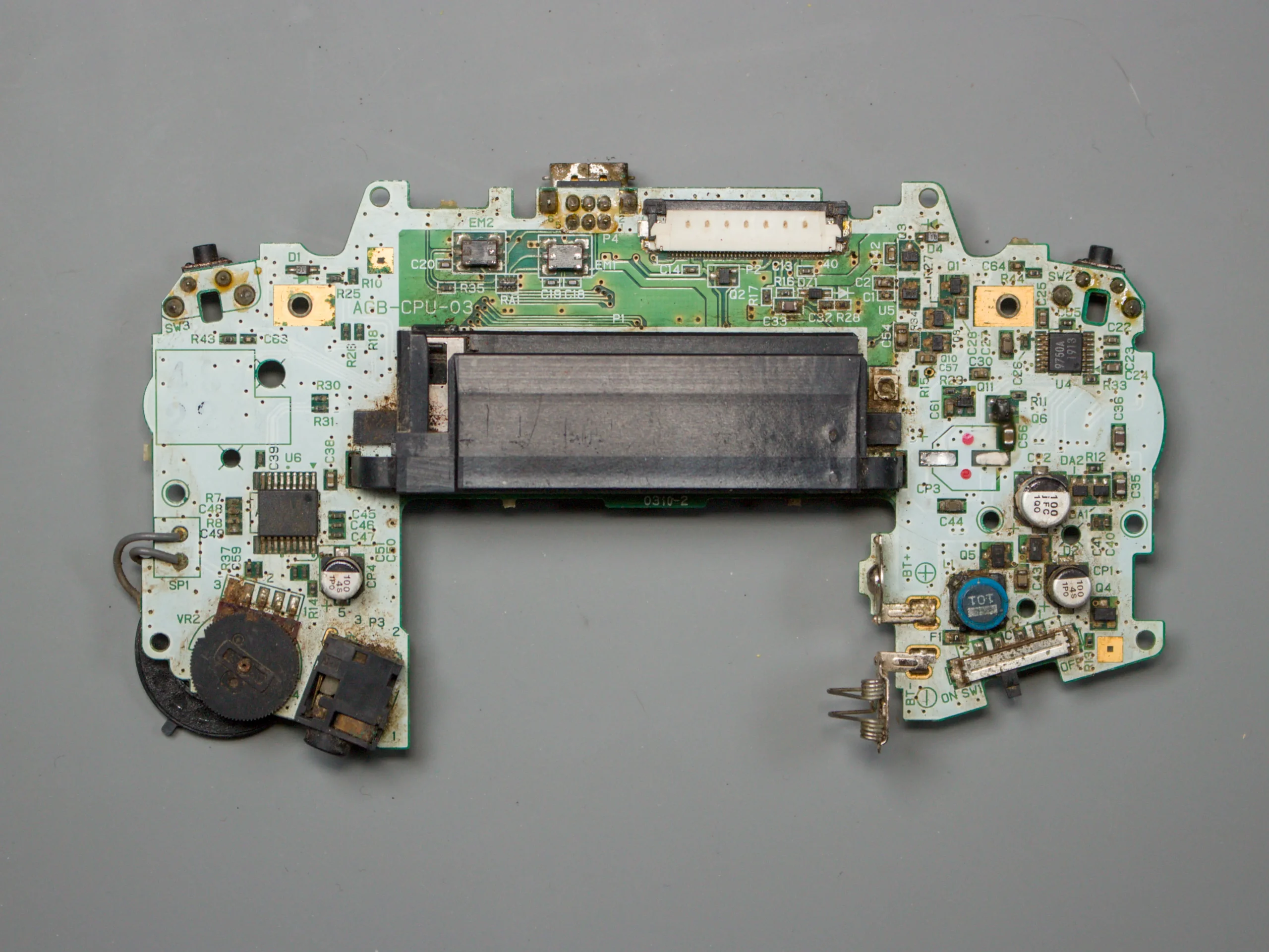 Rear side of a Game Boy Advance motherboard showing corrosion around the power and audio circuitry