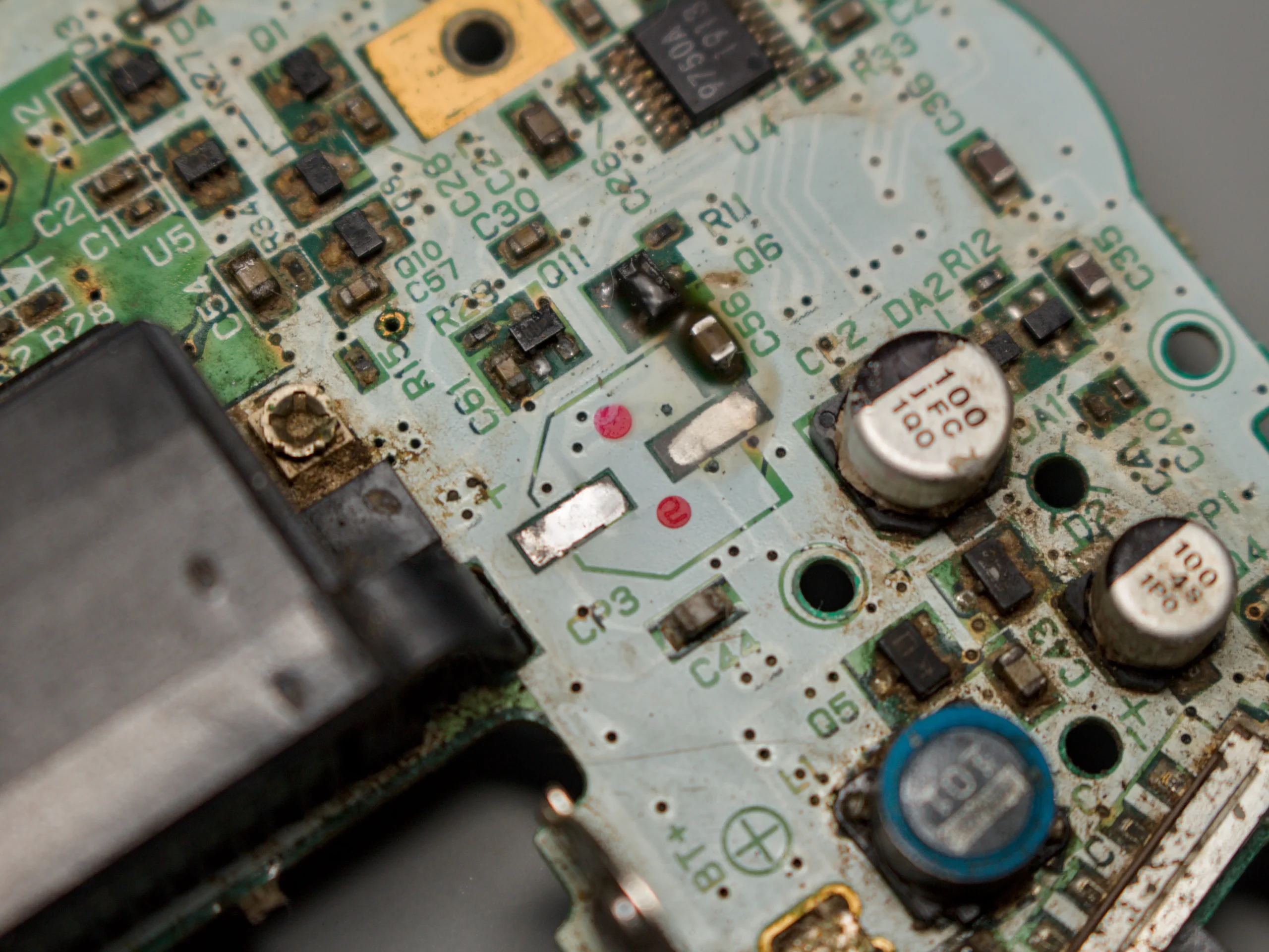 Close-up of corrosion and damaged components in the Game Boy Advance power circuit
