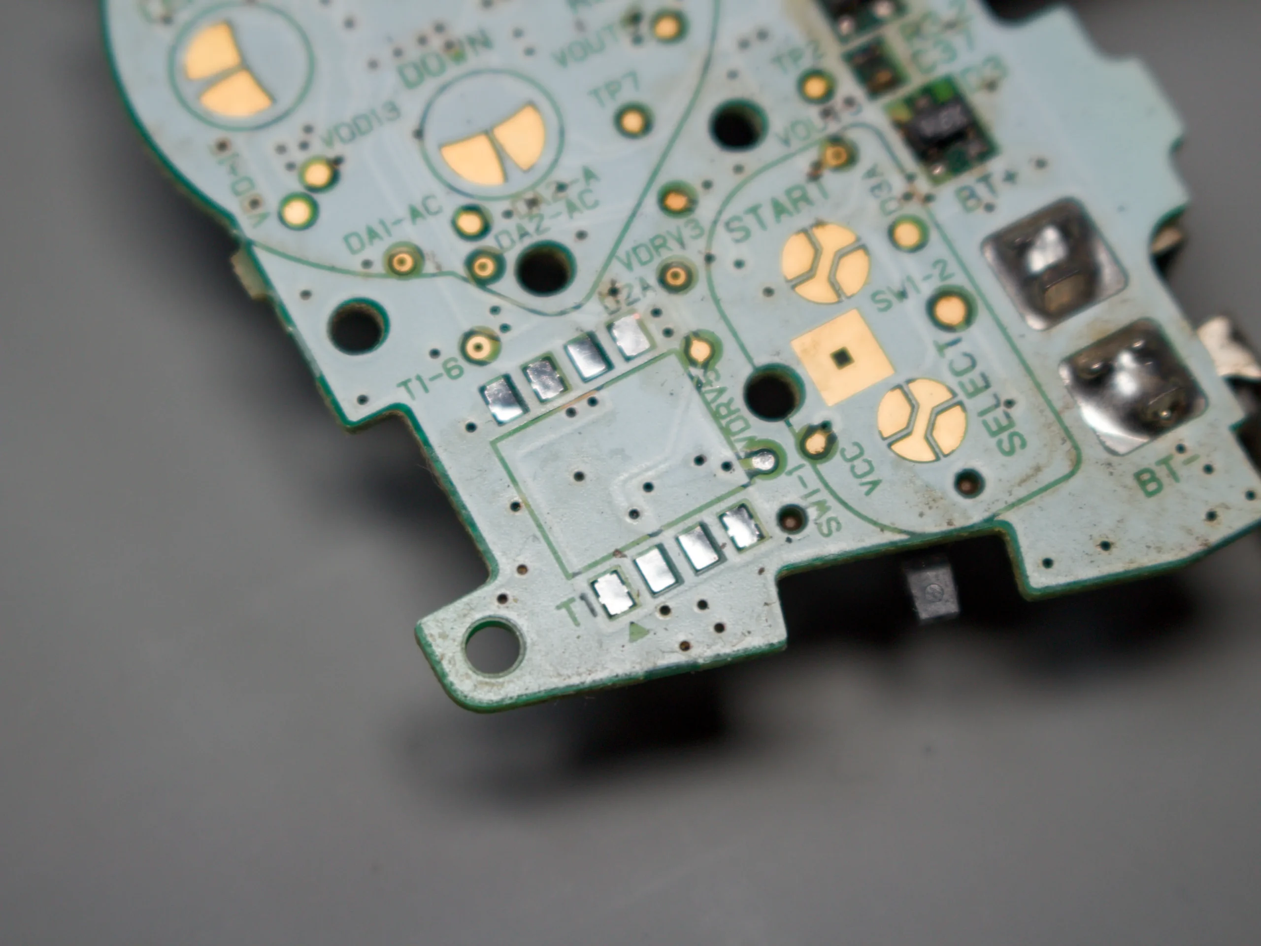 Close-up of an empty component footprint and solder pads near the START and SELECT button contacts on a Game Boy Advance motherboard