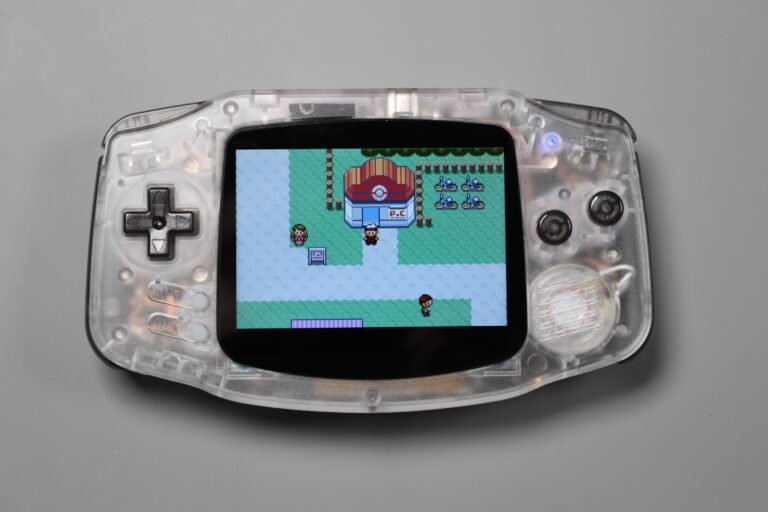Clear-shell Game Boy Advance powered on and displaying a Pokémon game