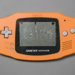 Orange Game Boy Advance with a badly damaged and scratched LCD screen