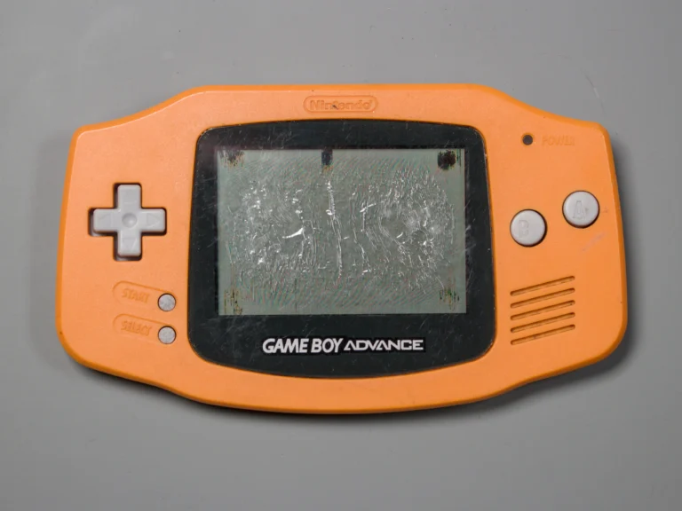 Orange Game Boy Advance with a badly damaged and scratched LCD screen